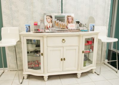 A white dresser with hair products and pictures of different hair styles at Details Salon & Spa
