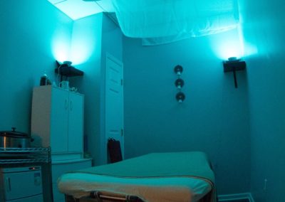 A relaxing massage room with dim lighting and a massage table at Details Salon & Spa